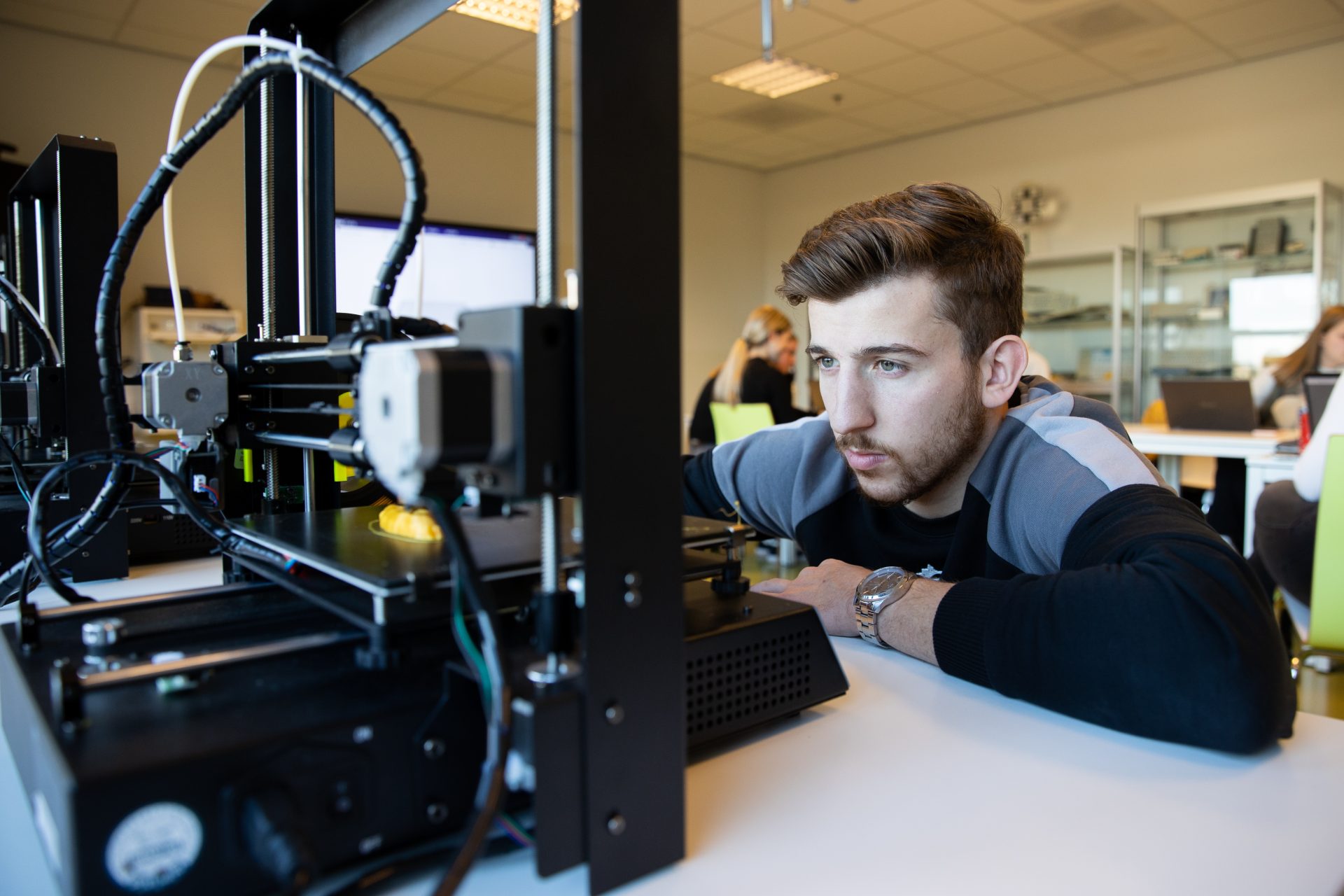 Een leerling bekijkt de voortgang van zijn print op de 3D printer.