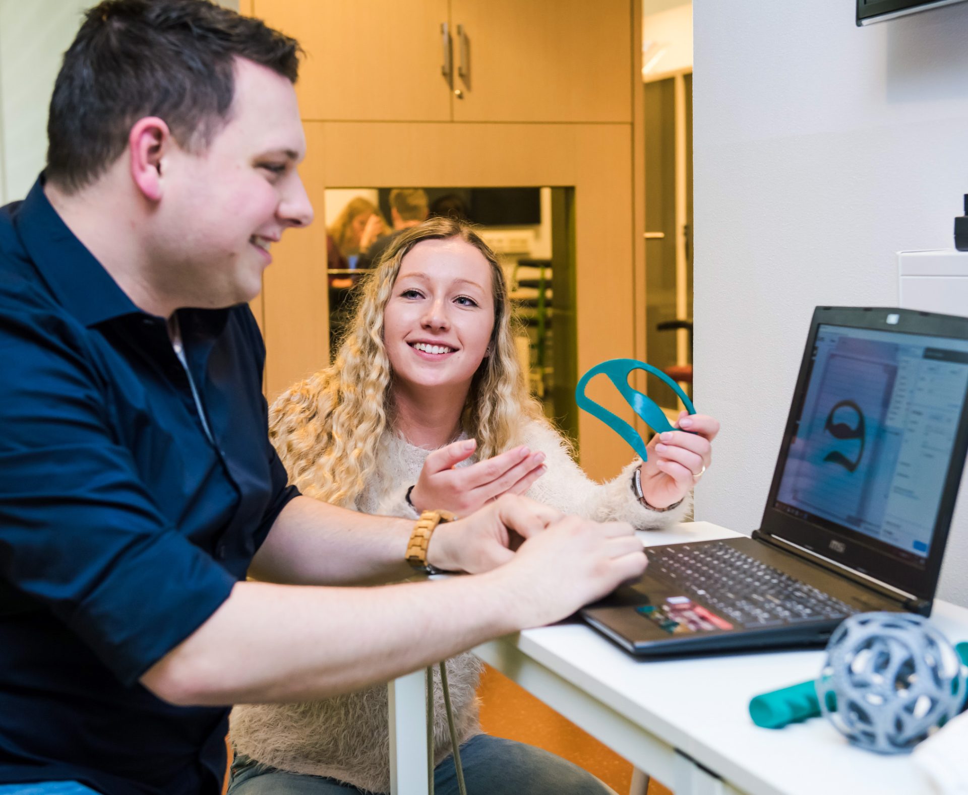 2 Personen vergelijken een 3d geprint model met het 3d model op de computer.